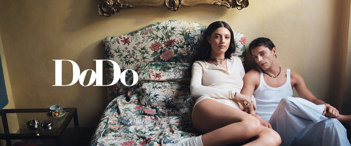 Zwei Modelle mit DoDo Goldschmuck auf einem Sofa, daneben der DoDo Schriftzug
