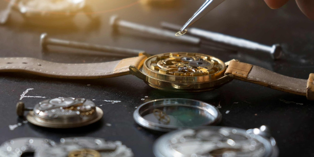 Uhrmacher ölt ein geöffnetes Uhrwerk in der Werkstatt von Juwelier Lun in München